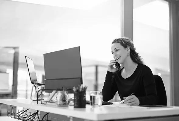 businesswoman talking on a cellphone while working on a computer